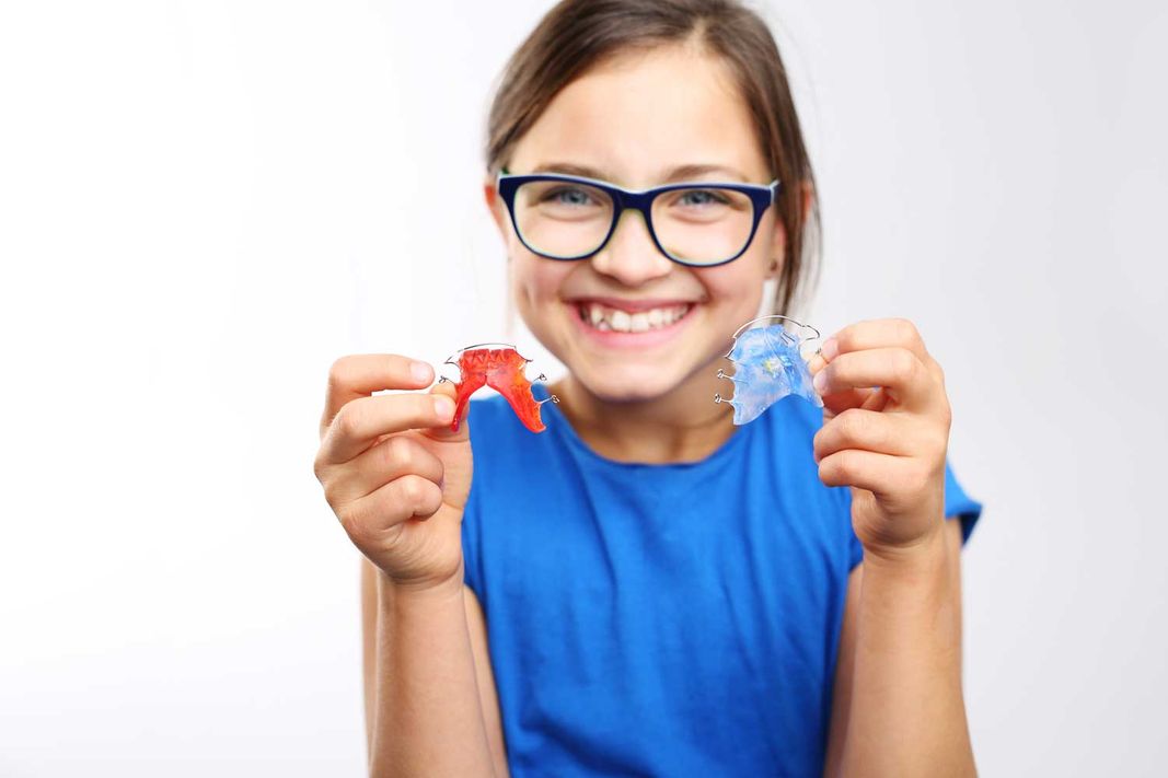 Kind mit abnehmbaren Zahnspangen in verschiedenen Farben
